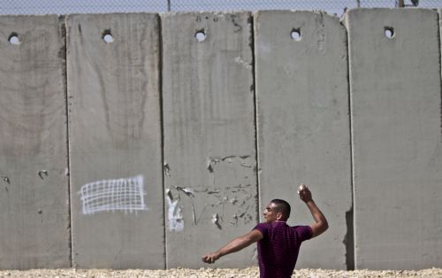 A Palestinian hurls stones towards Israeli soldiers during a demonstration against Israeli closure in Qalandiya checkpoint near Jerusalem city on March 13, 2010. 