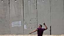 A Palestinian hurls stones towards Israeli soldiers during a demonstration against Israeli closure in Qalandiya checkpoint near Jerusalem city on March 13, 2010.