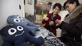 Tourists try to weave mascot Haibao at Farmhouse Homestays of Expo in Shanghai, east China, March 13, 2010. Farmhouse of the Shanghai World Expo, served as eco-friendly countryside temporary 'hotel' or 'inn' during the Shanghai World Expo by virtue of rural advantageous tourist resources, entered district of suburban Shanghai for the first time.