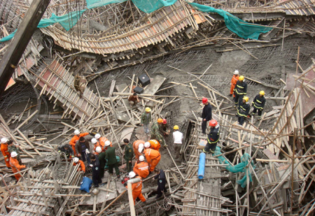 Chinese rescuers examine the debris of a collapsed passage that connects two halls of the Guiyang International Exhibition Center under construction in Guiyang, Southwest China's Guizhou Province, March 14, 2010. 