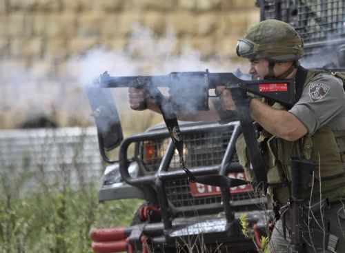 An Israeli soldier fires tear gas grenade towards Palestinian protesters during clashes at Atara Checkpoint in the north of the West Bank city of Ramallah, on March 15, 2010. 