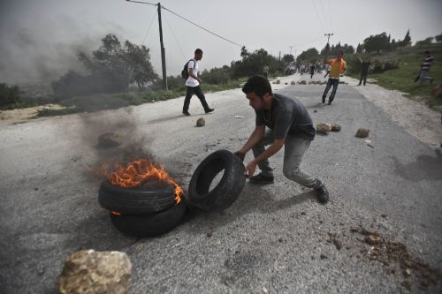 A Palestinian protester burns tires during clashes with Israeli troops at Atara Checkpoint in the north of the West Bank city of Ramallah, on March 15, 2010.