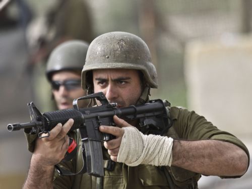 An Israeli soldier aims his rifle towards Palestinian protesters during clashes at Atara Checkpoint in the north of the West Bank city of Ramallah, on March 15, 2010. 