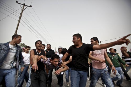 Palestinian protesters carry a wounded youth during clashes with Israeli troops at Atara Checkpoint in the north of the West Bank city of Ramallah, on March 15, 2010.