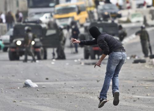 A Palestinian protester hurls stones at Israeli soldiers during clashes at Qalandiya checkpoint near the West Bank city of Ramallah on March 17, 2010. 