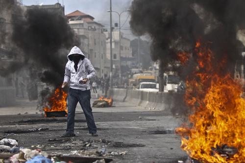 A Palestinian protester hurls stones at Israeli soldiers during clashes at Qalandiya checkpoint near the West Bank city of Ramallah on March 17, 2010. 