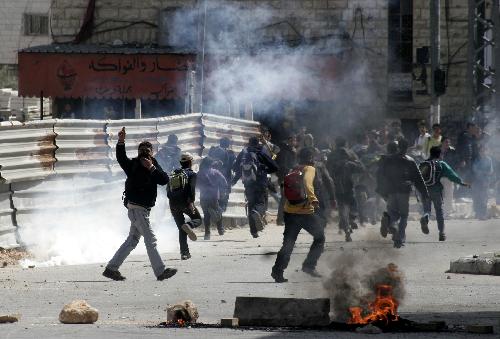 Palestinian protesters run to take cover during clashes with Israeli soldiers in the West Bank city of Hebron on March 17, 2010. 