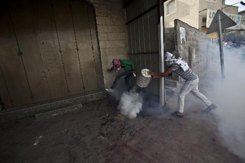 Palestinian protesters tries to deactivate a tear gas canister during clashes at Qalandiya checkpoint near the West Bank city of Ramallah on March 17, 2010.