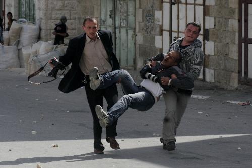 Palestinians carry a wounded photographer during clashes with Israeli soldiers in the West Bank city of Hebron on March 17, 2010. 