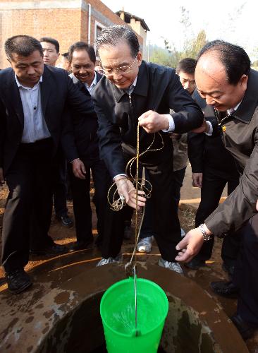 Chinese Premier Wen Jiabao (C Front) fetches water from a well at Damaidi Village of Kuishan Town in Shizong County, southwest China&apos;s Yunnan Province, March 20, 2010. 