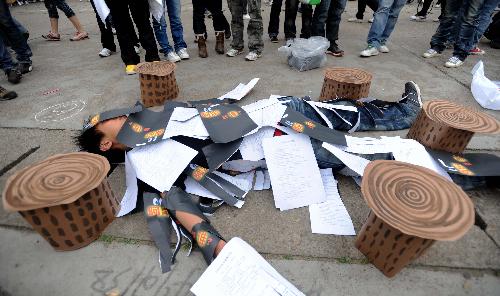 A college student lies in a feign scene of tree stumps and wasted papers during the launching ceremony of 2010 Earth Hour Changsha in Changsha, capital of central China's Hunan Province, March 21, 2010. 