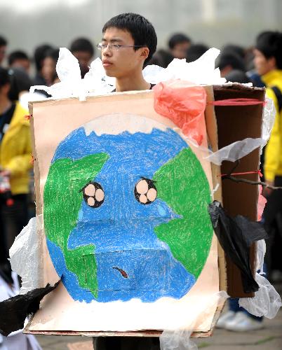 A college student displays a poster of the earth being surrounded by plastics during the launching ceremony of 2010 Earth Hour Changsha in Changsha, capital of central China's Hunan Province, March 21, 2010. 