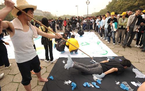 Two college students simulate the scene of hunting a cowfish during the launching ceremony of 2010 Earth Hour Changsha in Changsha, capital of central China's Hunan Province, March 21, 2010. 