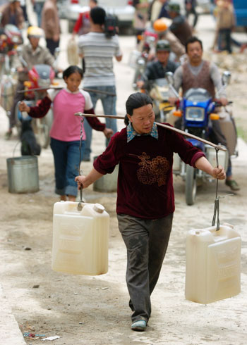 People carry drinking water at a water supply point of Wenqian village at Dongshan Township in Bama Yao Autonomous County, southwest China's Guangxi Zhuang Autonomous Region, March 23, 2010. 