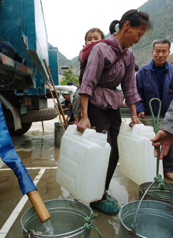 People carry drinking water at a water supply point of Wenqian village at Dongshan Township in Bama Yao Autonomous County, southwest China's Guangxi Zhuang Autonomous Region, March 23, 2010.