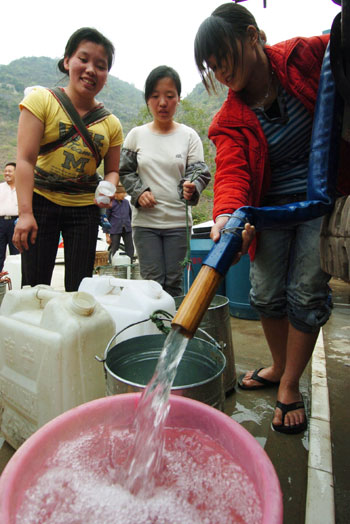 A woman pours drinking water into barrels at a water supply point of Wenqian village at Dongshan Township in Bama Yao Autonomous County, southwest China's Guangxi Zhuang Autonomous Region, March 23, 2010. 