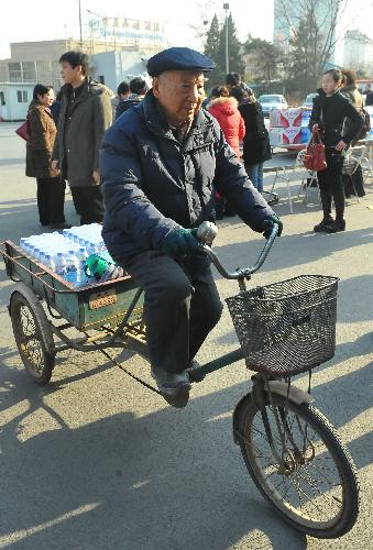 An elder man rides his Trishaws sending drinking waters to a donation site at Fengtai Sports Center in Beijing, China, March 28. 2010.