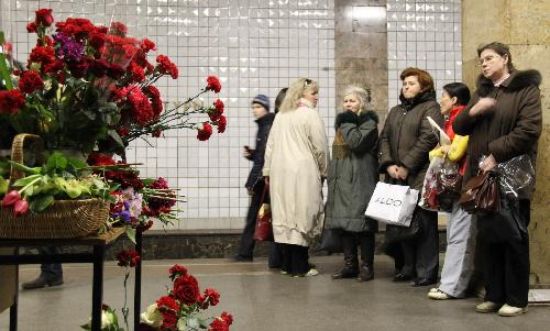 People stand in front of flowers in memory of the bomb victims at the Cultural Park subway station in Moscow, capital of Russia, March 29, 2010. 