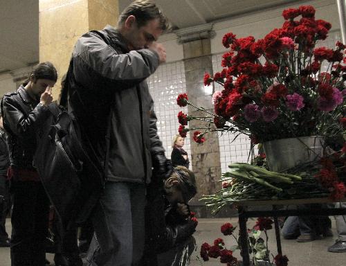 People pray in front of flowers in memory of the bomb victims at the Cultural Park subway station in Moscow, capital of Russia, March 29, 2010.