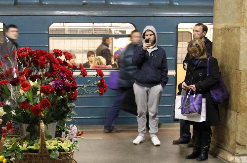 Commuters stand in front of flowers in memory of the bomb victims at the Cultural Park subway station in Moscow, capital of Russia, March 29, 2010. 