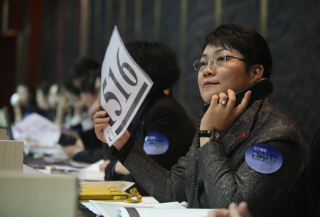 A woman submits a bid during a charity auction at China Guardian Auction Co Ltd that was in aid of quake-ravaged Haiti.