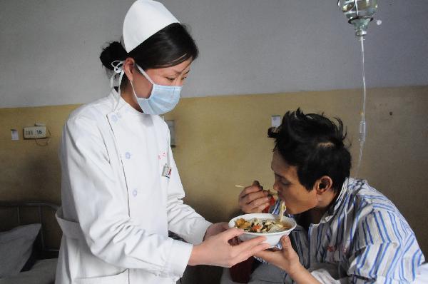 A nurse helps a rescued miner of the flooded Wangjialing Coal Mine eating noodles at Shanxi Aluminum Factory Worker's Hospital in north China's Shanxi Province, April 6, 2010. 