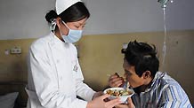 A nurse helps a rescued miner of the flooded Wangjialing Coal Mine eating noodles at Shanxi Aluminum Factory Worker's Hospital in north China's Shanxi Province, April 6, 2010.