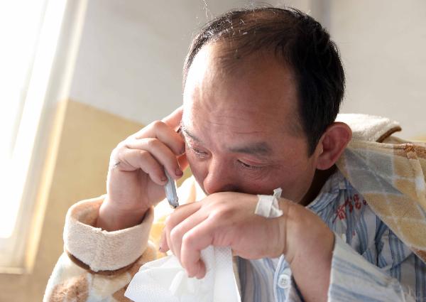 Cheng Quanzhong, a survivor of flooded Wangjialing Coal Mine, weeps while having a phone call with his younger brother Cheng Xiaozhong at a hospital in Hejin City of north China's Shanxi Province, on April 8, 2010. 