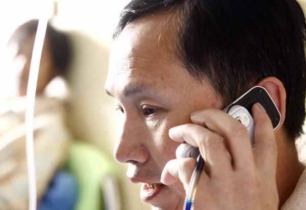 Wang Renfang, a survivor of flooded Wangjialing Coal Mine, has a phone call with his wife at a hospital in Hejin City of north China's Shanxi Province, on April 8, 2010. 