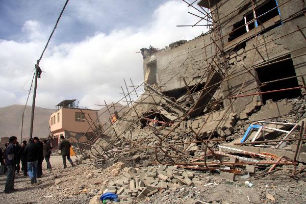 People stand near the ruins of collapsed houses after a quake in Yushu County, northwest China's Qinghai Province, April 14, 2010.