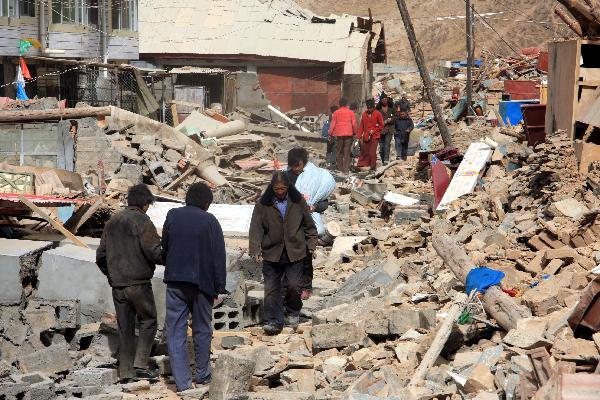 People walk on the ruins of collapsed houses after a quake in Yushu County, northwest China's Qinghai Province, April 14, 2010.