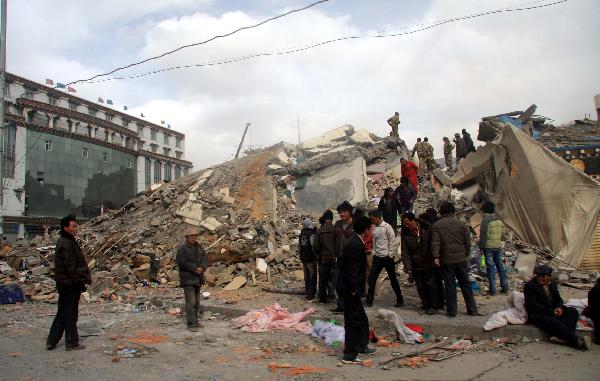People stand near the ruins of collapsed houses after a quake in Yushu County, northwest China's Qinghai Province, April 14, 2010. 