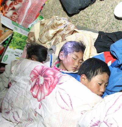 Children sleep in the open air as their parents build up a tent after a quake in Yushu County, northwest China's Qinghai Province, April 14, 2010. 