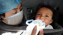 A nurse feeds milk to a baby in a medical shelter in Yushu, the quake-hit area on April 15, 2010.
