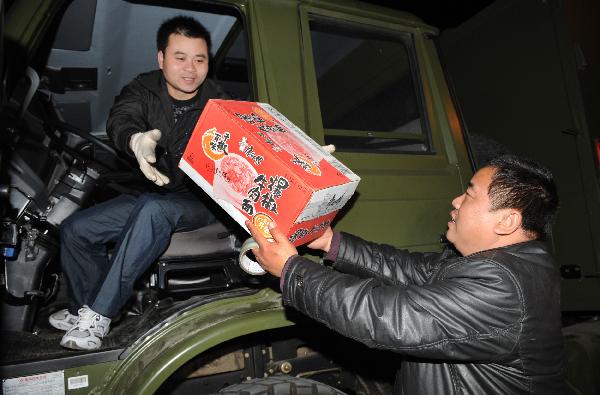 A driver on of the array of some 39 full-equipped plateau proper-functional kitchen trucks takes in the box of instant noodles upon setting out en route for the quake-jolted zone in Yushu of Qinghai, at Lu'an City, east China's Anhui Province, April 15, 2010. 