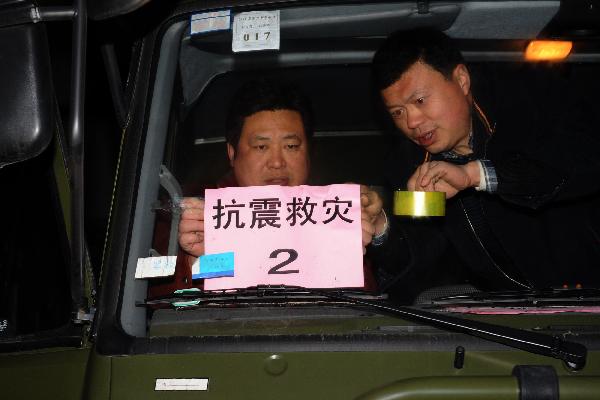 Drivers affix the placard of Quake-Disaster Relief onto the windshield of one of the array of some 39 full-equipped plateau proper-functional kitchen trucks upon setting out en route for the quake-jolted zone in Yushu of Qinghai, at Lu'an City, east China's Anhui Province, April 15, 2010.