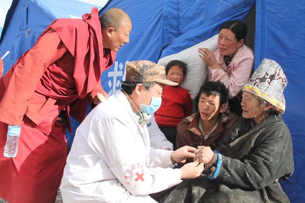 A military doctor cures an elder at a military tent hospital in Gyegu Town of earthquake hit Yushu County of northwest China's Qinghai Province, April 16, 2010. Dozens of medical team have rushed to Yushu from all over China since the 7.1-magnitude quake struck here early Wednesday.