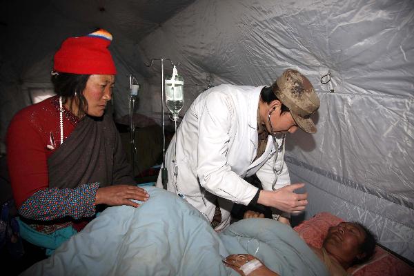 A military doctor checks an injured at a military tent hospital in Gyegu Town of earthquake hit Yushu County of northwest China's Qinghai Province, April 16, 2010. Dozens of medical team have rushed to Yushu from all over China since the 7.1-magnitude quake struck here early Wednesday.