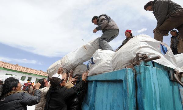 Earthquake victims receive relief materials at a distribution station in Longbao Town of the quake-hit Yushu County,northwest China's Qinghai Province, April 16, 2010. Rescue operations continued in Yushu to save more lives during the'golden 72 hours'since the 7.1-magnitude quake struck here early Wednesday.