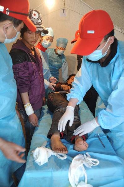 Medical workers treat an injured woman in quake-hit Yushu County, northwest China's Qinghai Province, April 16, 2010.