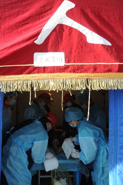 Medical workers treat an injured woman in quake-hit Yushu County, northwest China's Qinghai Province, April 16, 2010. 
