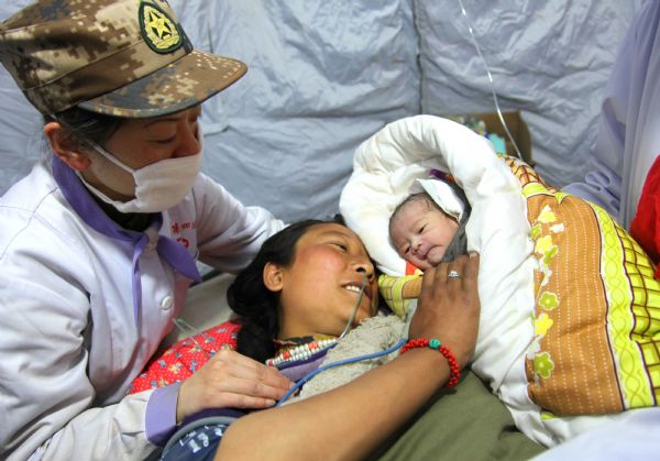 Ga Yong (C), a 22-year-old woman who just gave birth to a baby girl in a tent hospital, looks at her daughter in Gyegu Town, northwest China&apos;s Qinghai Province, on April 17, 2010