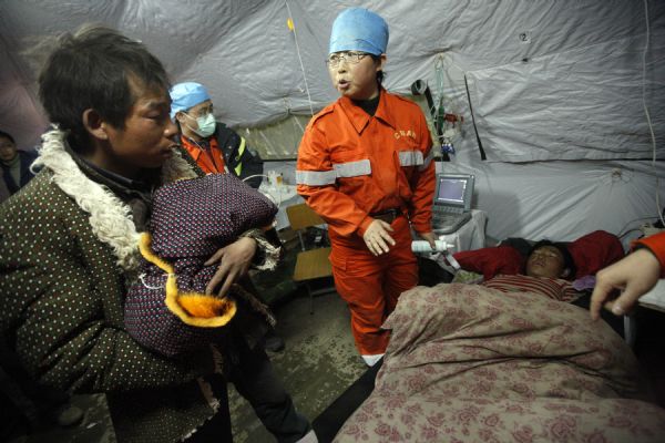 A man holds his newborn child at a makeshift shelter in Gyegu Town, Yushu County, northwest China&apos;s Qinghai Province, on April 17, 2010. 