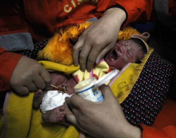 Medical personnel disinfect a newborn baby at a makeshift shelter in Gyegu Town, Yushu County, northwest China&apos;s Qinghai Province, on April 17, 2010. 