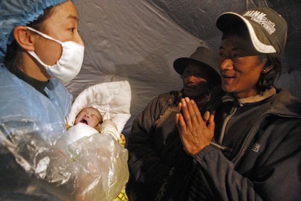 Father of a newborn baby (R) thanks a doctor at a makeshift shelter in Gyegu Town, Yushu County, northwest China&apos;s Qinghai Province, on April 17, 2010