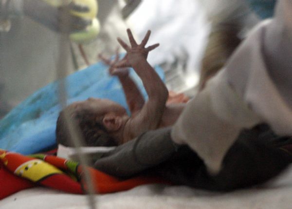 A newborn baby is seen with her mother at a makeshift shelter in Gyegu Town, Yushu County, northwest China's Qinghai Province, on April 17, 2010.