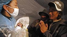 Father of a newborn baby (R) thanks a doctor at a makeshift shelter in Gyegu Town, Yushu County, northwest China's Qinghai Province, on April 17, 2010.