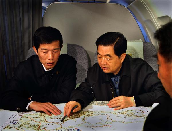 Chinese President Hu Jintao (C) looks at a map of the Tibetan Autonomous Prefecture of Yushu, northwest China's Qinghai Province on the plane heading to Yushu, April 18, 2010. 