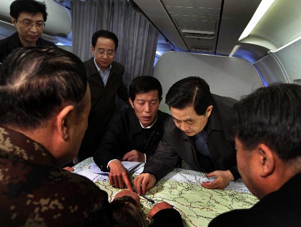 Chinese President Hu Jintao (2nd R) looks at a map of the Tibetan Autonomous Prefecture of Yushu, northwest China's Qinghai Province on the plane heading to Yushu, April 18, 2010. 