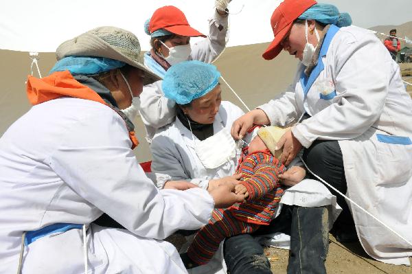 Medical staff of a medical team feed a baby with milk in a bottle in the Tibetan Autonomous Prefecture of Yushu, northwest China's Qinghai Province, April 18, 2010. 